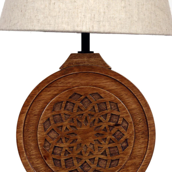 Bohemian-style table lamp with a round, carved wood mandala base and a neutral fabric lampshade