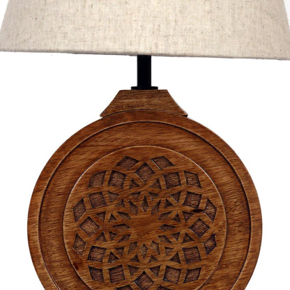 Bohemian-style table lamp with a round, carved wood mandala base and a neutral fabric lampshade