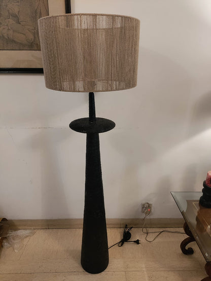 A minimalist sculptural floor lamp showcasing a matte black textured column base paired with a beige string-detailed lampshade.