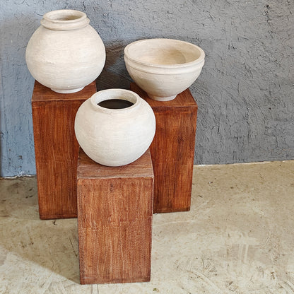 Minimalist wooden display risers holding handcrafted white clay vases in a multi-level arrangement.