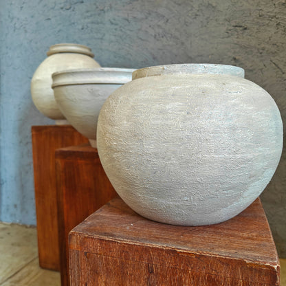 Minimalist wooden display risers holding handcrafted white clay vases in a multi-level arrangement.
