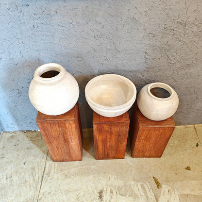 Minimalist wooden display risers holding handcrafted white clay vases in a multi-level arrangement.