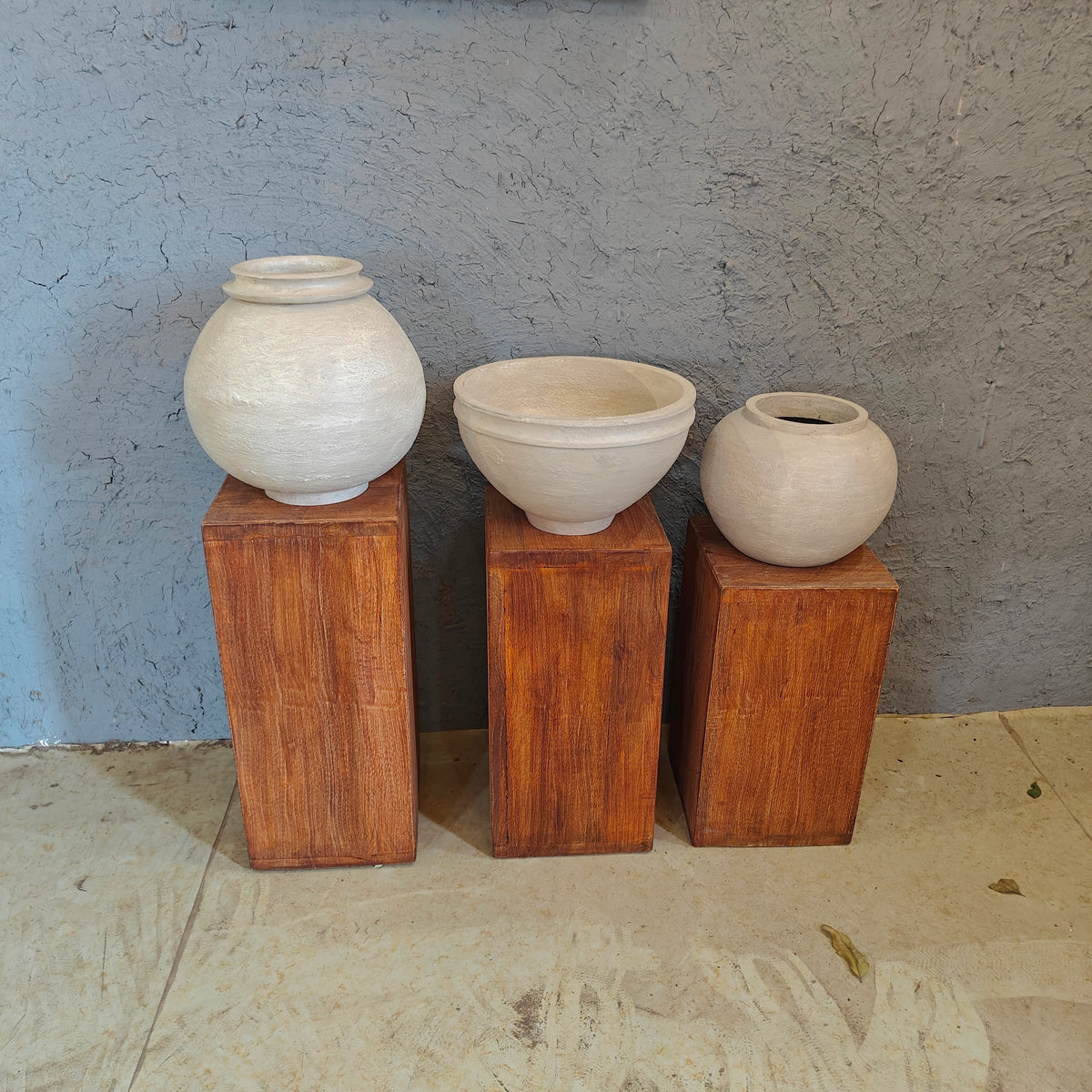 Minimalist wooden display risers holding handcrafted white clay vases in a multi-level arrangement.