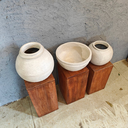 Minimalist wooden display risers holding handcrafted white clay vases in a multi-level arrangement.