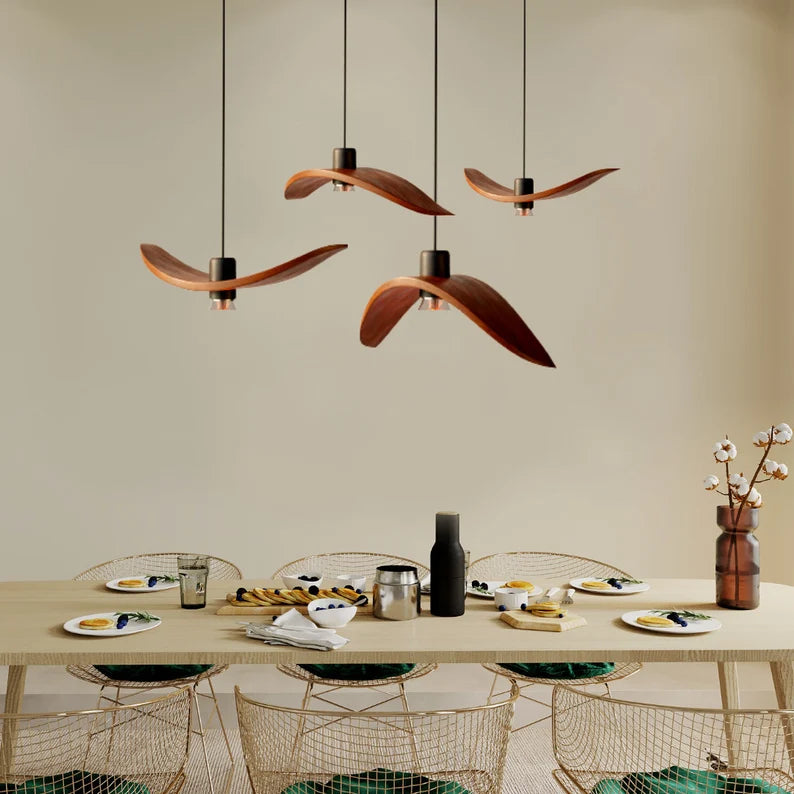 Minimalist Scandinavian ceiling chandelier featuring four bird-wing-shaped natural wood shades dangling at adjustable heights.