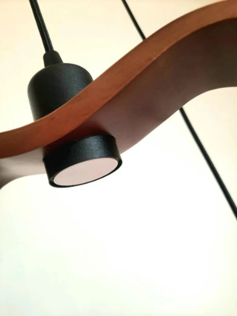 Minimalist Scandinavian ceiling chandelier featuring four bird-wing-shaped natural wood shades dangling at adjustable heights.