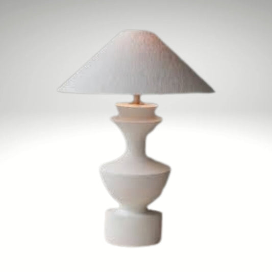 Sculptural ceramic table lamp in white with a wide cone shade resting on a flat surface.