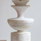 Sculptural ceramic table lamp in white with a wide cone shade resting on a flat surface.