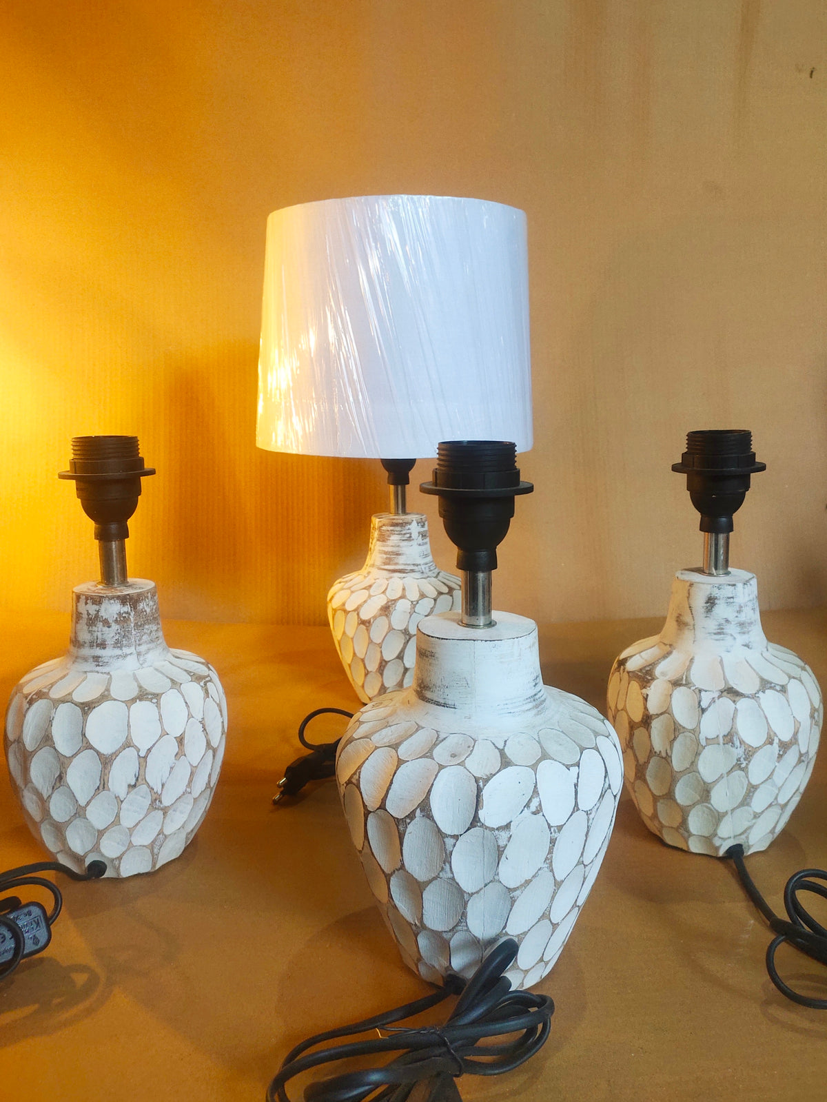 Cream-colored bedside lamp with a sculptural, stone-textured oval base and a clean white fabric lampshade.