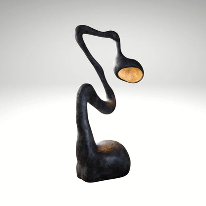Biomorphic black floor lamp featuring a curved snake-like body and warm internal glow.
