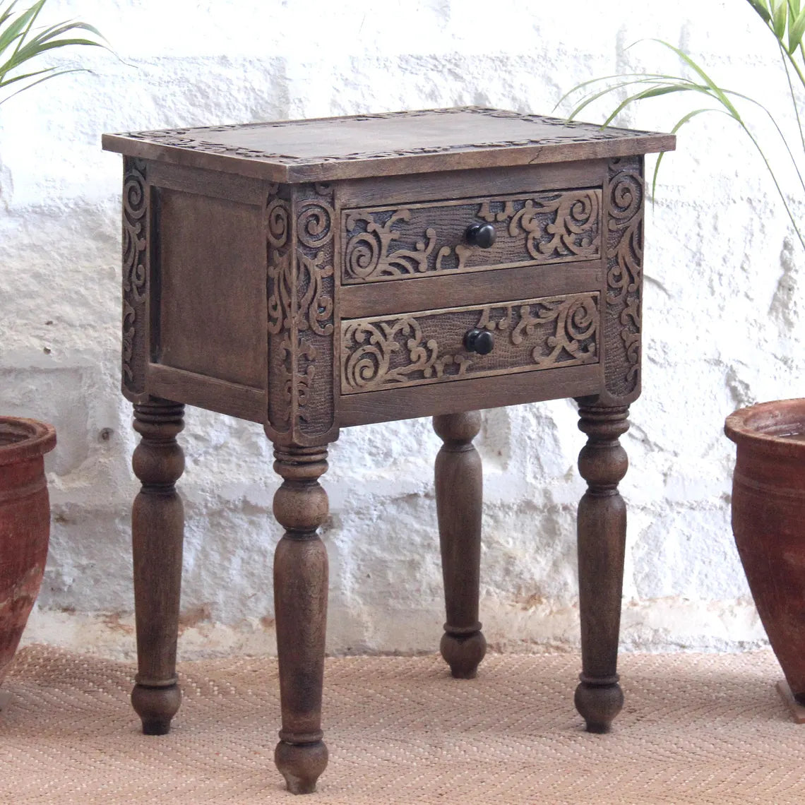 Traditional brown wooden side table featuring intricate floral carvings on two drawers