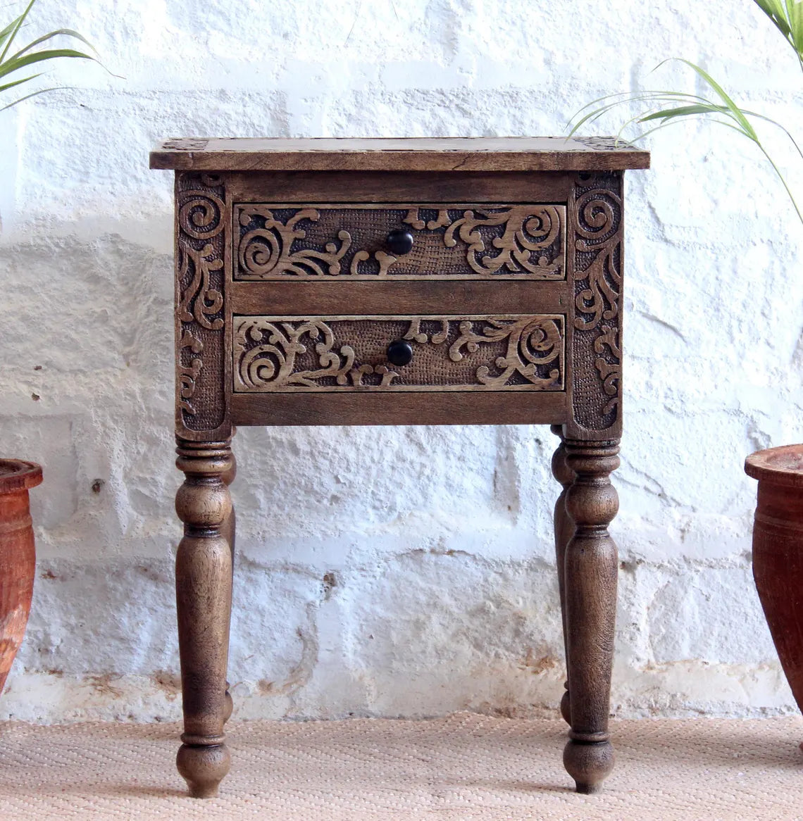 Traditional brown wooden side table featuring intricate floral carvings on two drawers