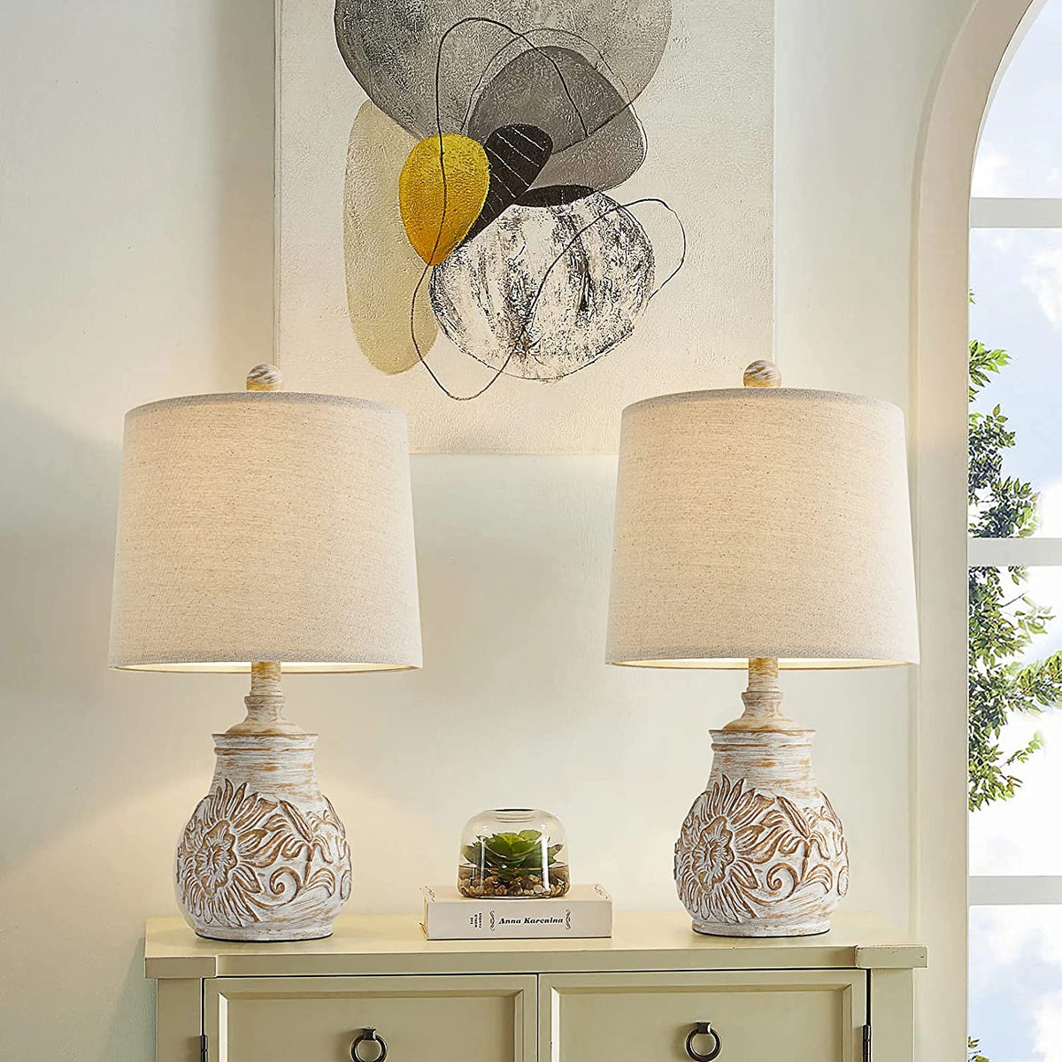 Distressed white ceramic table lamp with a carved sunflower base and a beige fabric drum shade.