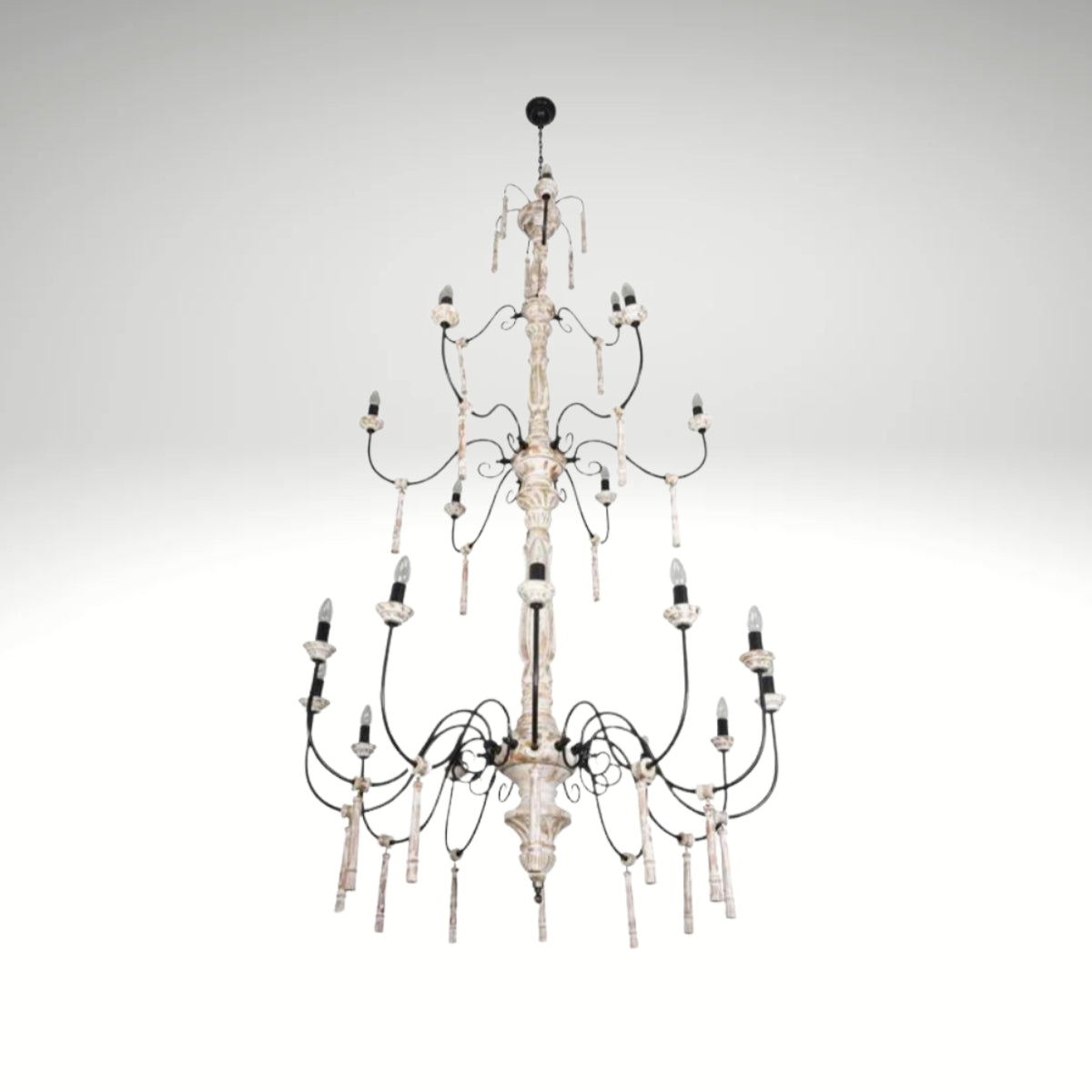 A multi-tiered rustic white chandelier with distressed wood columns and black iron scrolled arms.