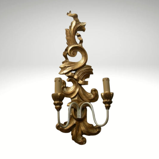 Ornate gold baroque wall sconce with a dual candle light fixture.
