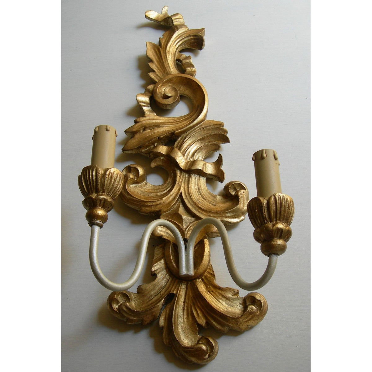 Ornate gold baroque wall sconce with a dual candle light fixture.
