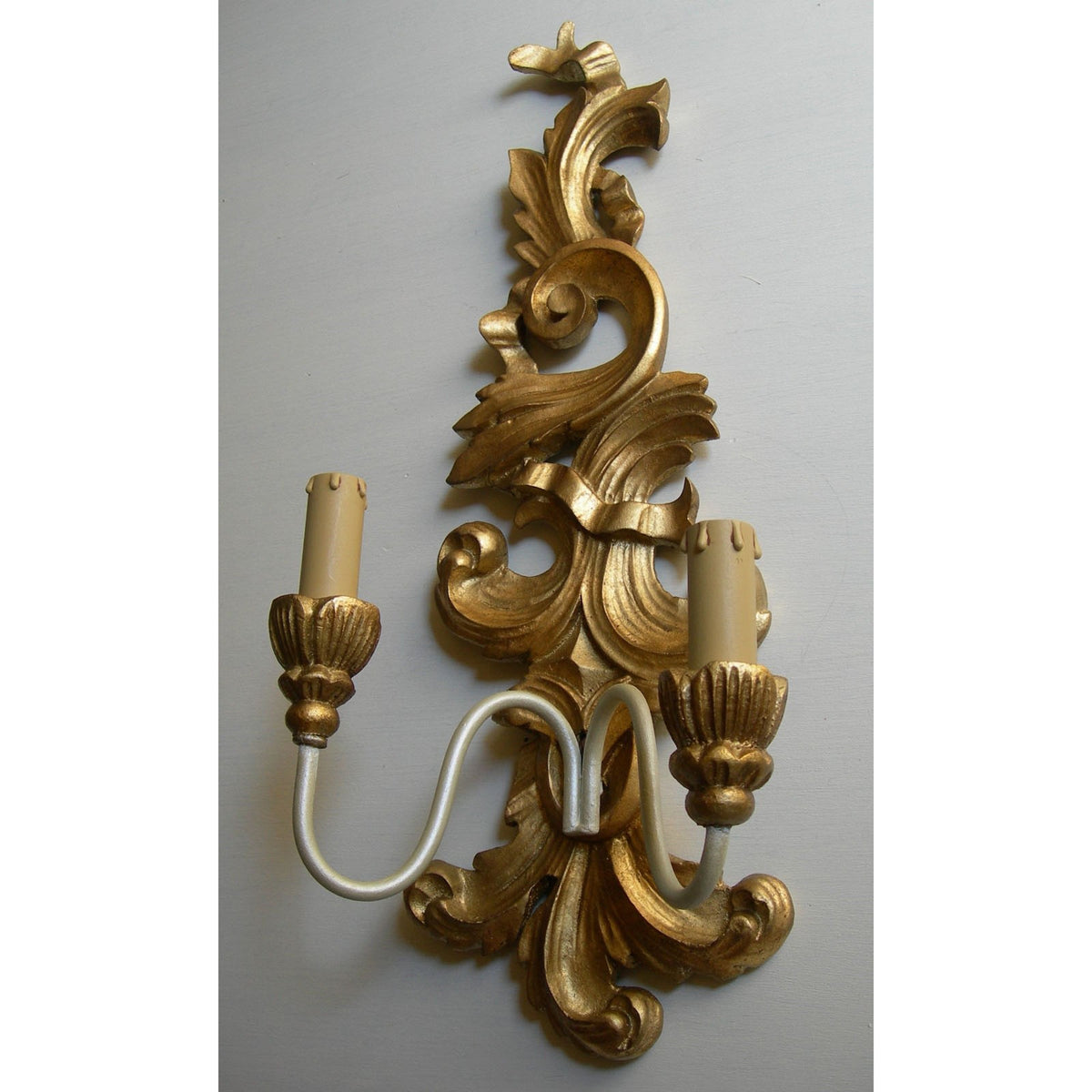 Ornate gold baroque wall sconce with a dual candle light fixture.
