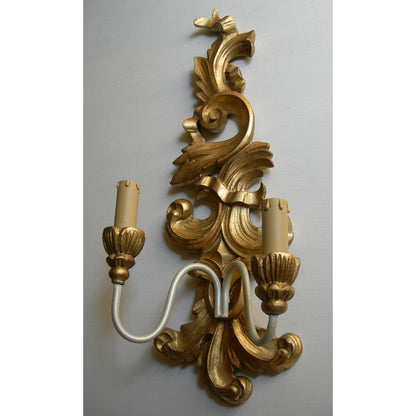 Ornate gold baroque wall sconce with a dual candle light fixture.
